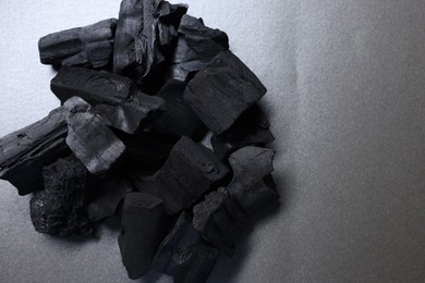 Photo of Pieces of black coals on grey table, top view. Space for text