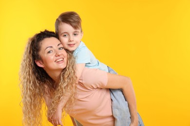 Photo of Family. Happy mother and her son on yellow background. Space for text