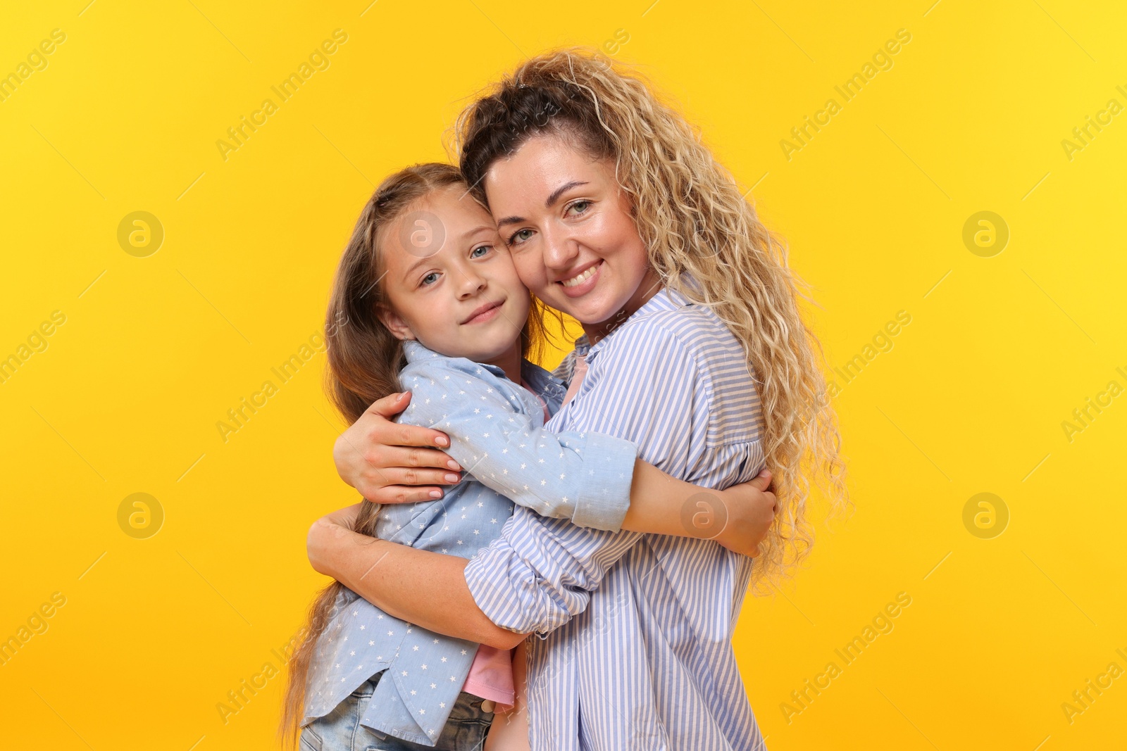 Family. Happy mother hugging her daughter on yellow background Photo of Family. Happy mother hugging her daughter on yellow background