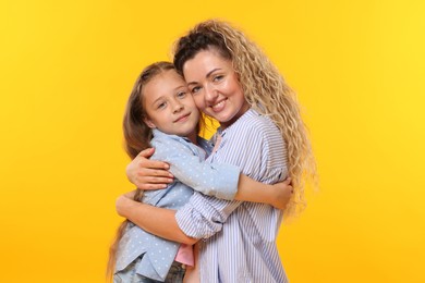 Photo of Family. Happy mother hugging her daughter on yellow background