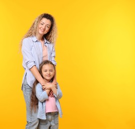 Photo of Family. Happy mother and her daughter on yellow background. Space for text