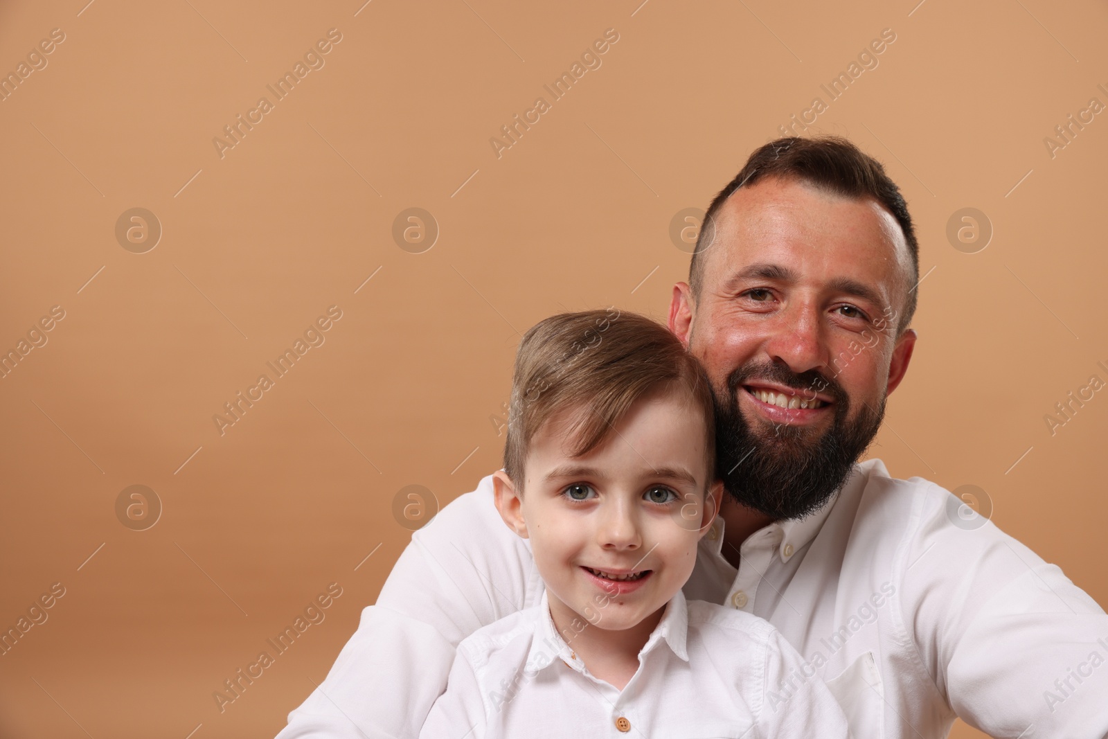 Family portrait of happy father and his son on beige background. Space for text Photo of Family portrait of happy father and his son on beige background. Space for text