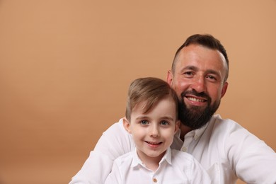 Photo of Family portrait of happy father and his son on beige background. Space for text