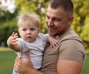 Photo of Smiling dad and his newborn baby outdoors. Happy Father's Day