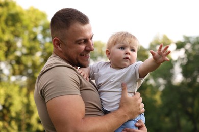 Photo of Smiling dad and his newborn baby outdoors. Happy Father's Day