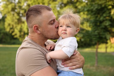 Photo of Dad kissing his cute newborn baby outdoors. Happy Father's Day