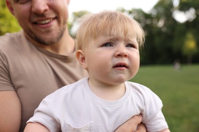 Photo of Smiling dad and his newborn baby outdoors, closeup. Happy Father's Day