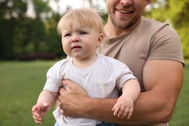 Photo of Smiling dad and his newborn baby outdoors, closeup. Happy Father's Day
