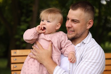 Photo of Smiling dad and his newborn girl on bench outdoors. Happy Father's Day