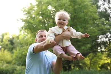 Photo of Smiling dad and his newborn baby playing outdoors. Happy Father's Day