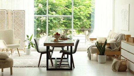Photo of Wooden table, chairs, sofa and decor in dining room. Interior design