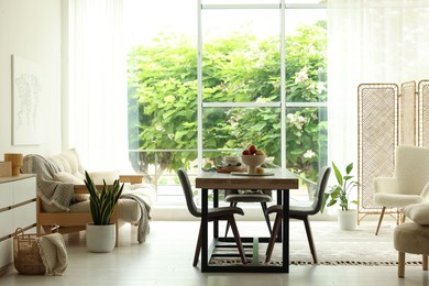 Photo of Wooden table, chairs, sofa and decor in dining room. Interior design