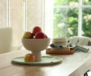 Photo of Apples and clean dishware on wooden table in dining room