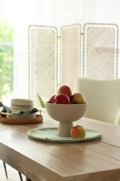 Photo of Apples and clean dishware on wooden table in dining room