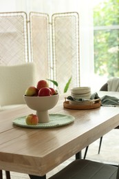 Photo of Apples and clean dishware on wooden table in dining room