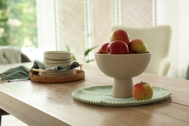 Photo of Apples and clean dishware on wooden table in dining room