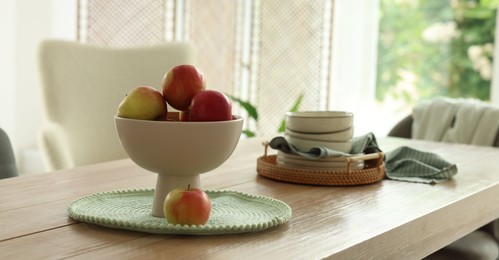 Photo of Apples and clean dishware on wooden table in dining room