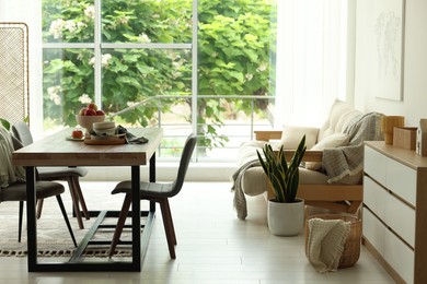 Photo of Wooden table, chairs, sofa and decor in dining room. Interior design
