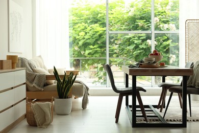 Photo of Wooden table, chairs, sofa and decor in dining room. Interior design