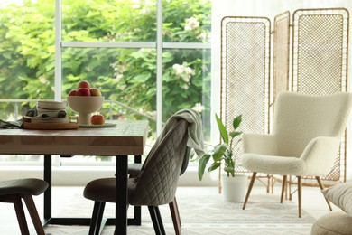 Photo of Wooden table, chairs, armchair and decor in dining room. Interior design
