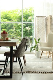 Photo of Wooden table, chairs, armchair and decor in dining room. Interior design