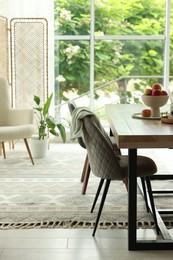Photo of Wooden table, chairs, armchair and decor in dining room. Interior design