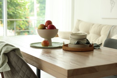 Photo of Apples and clean dishware on wooden table in dining room