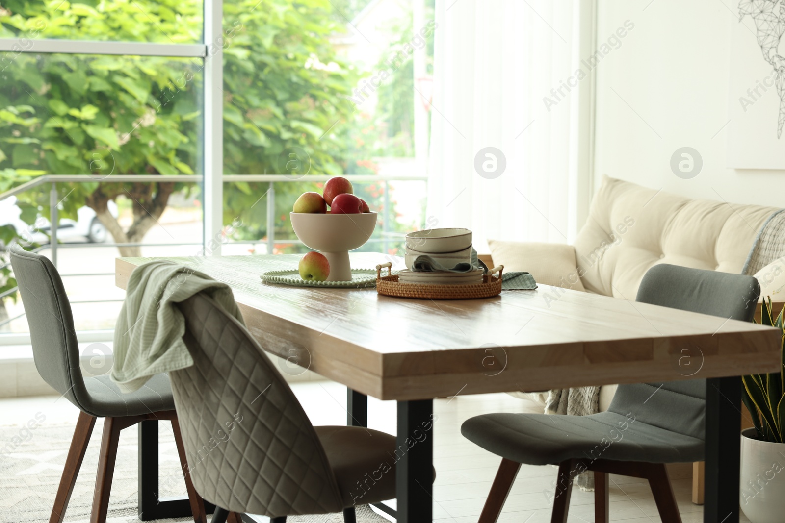 Wooden table, chairs, sofa and decor in dining room. Interior design Photo of Wooden table, chairs, sofa and decor in dining room. Interior design