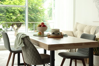 Photo of Wooden table, chairs, sofa and decor in dining room. Interior design