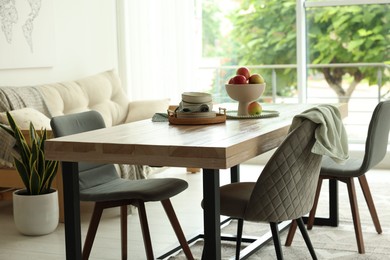 Photo of Wooden table, chairs, sofa and decor in dining room. Interior design