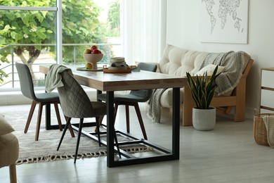 Photo of Wooden table, chairs, sofa and decor in dining room. Interior design