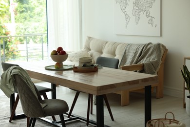 Photo of Wooden table, chairs, sofa and decor in dining room. Interior design