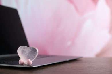 Photo of Online dating site. Decorative hearts and laptop on wooden table, closeup. Space for text