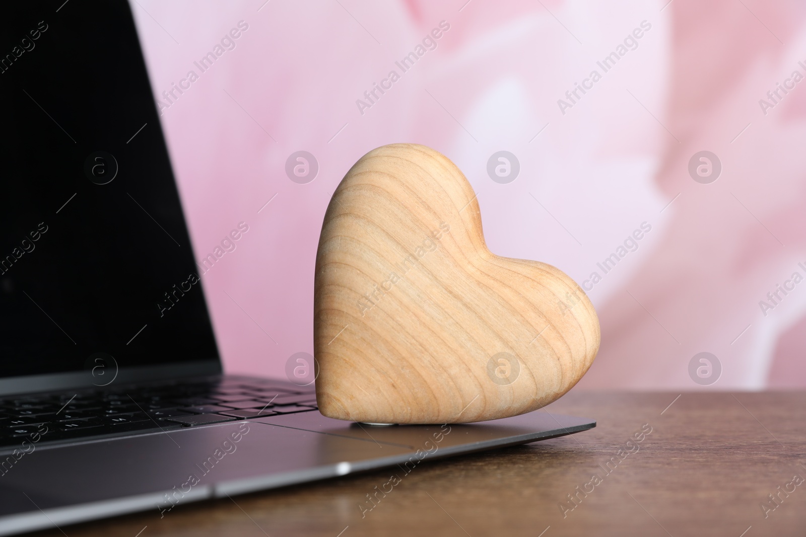 Wooden heart and laptop on table, closeup. Online dating site Photo of Wooden heart and laptop on table, closeup. Online dating site