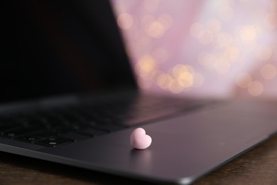 Photo of Online dating site. Decorative heart and laptop on table against blurred lights, closeup. Bokeh effect
