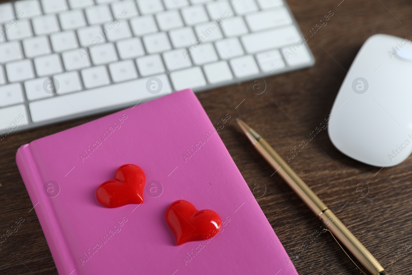 Decorative hearts, computer keyboard, mouse, notebook and pen on wooden table, closeup. Online dating site Photo of Decorative hearts, computer keyboard, mouse, notebook and pen on wooden table, closeup. Online dating site
