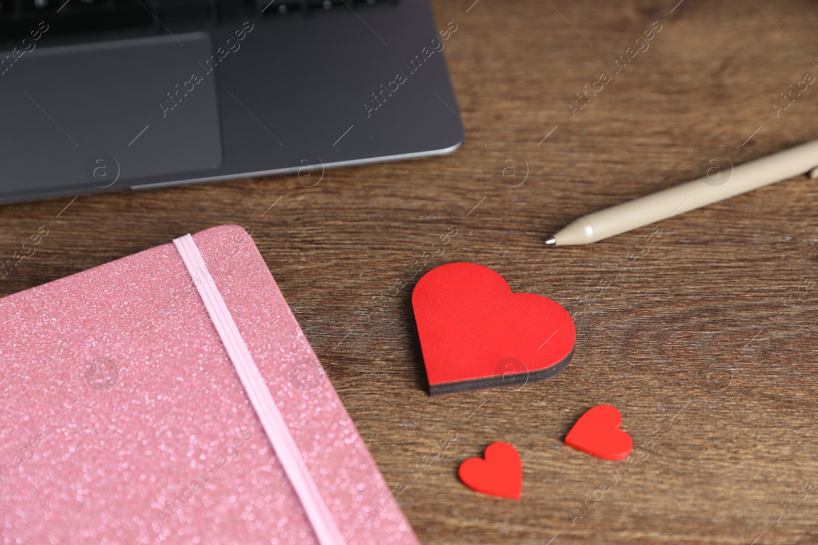 Decorative hearts, laptop, notebook and pen on wooden table, closeup. Online dating site Photo of Decorative hearts, laptop, notebook and pen on wooden table, closeup. Online dating site