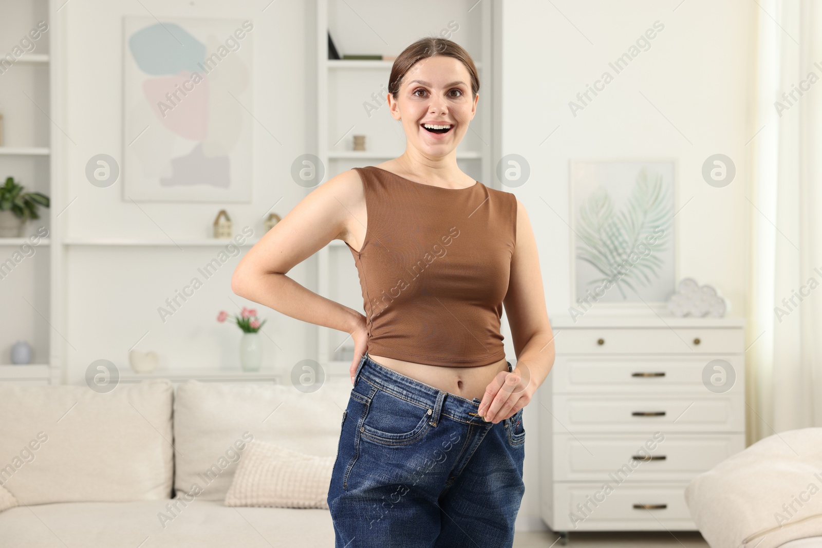 Beautiful woman wearing old jeans after weight loss indoors Photo of Beautiful woman wearing old jeans after weight loss indoors