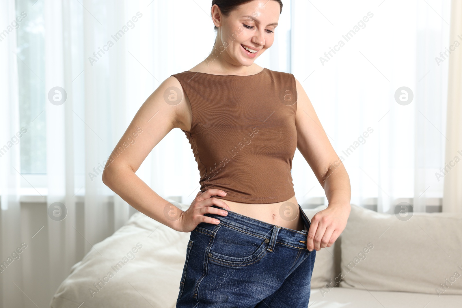 Beautiful woman wearing old jeans after weight loss indoors Photo of Beautiful woman wearing old jeans after weight loss indoors