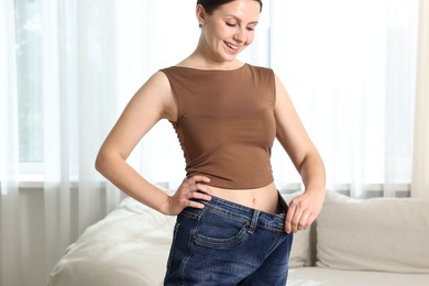 Photo of Beautiful woman wearing old jeans after weight loss indoors