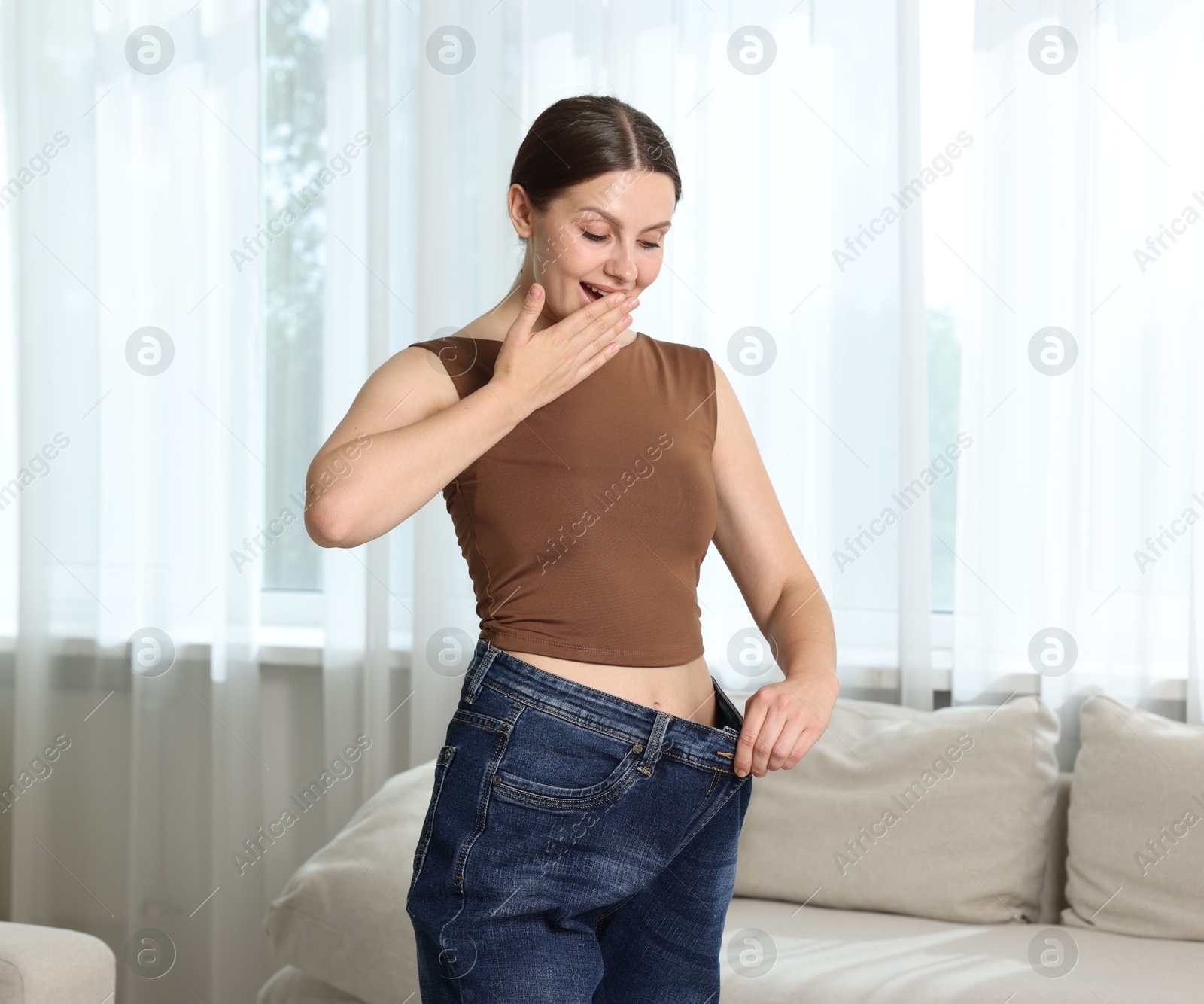 Photo of Beautiful woman wearing old jeans after weight loss indoors