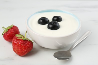 Photo of Tasty yoghurt with blueberries and strawberries in bowl on white marble table, closeup