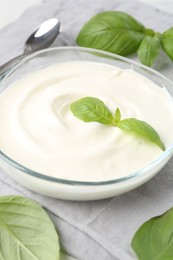 Photo of Tasty yoghurt with basil in bowl on table, closeup