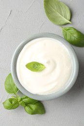 Photo of Tasty yoghurt with basil in bowl on light grey table, flat lay