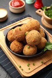 Photo of Delicious fried croquette balls with parsley and green onion on grey textured table, closeup
