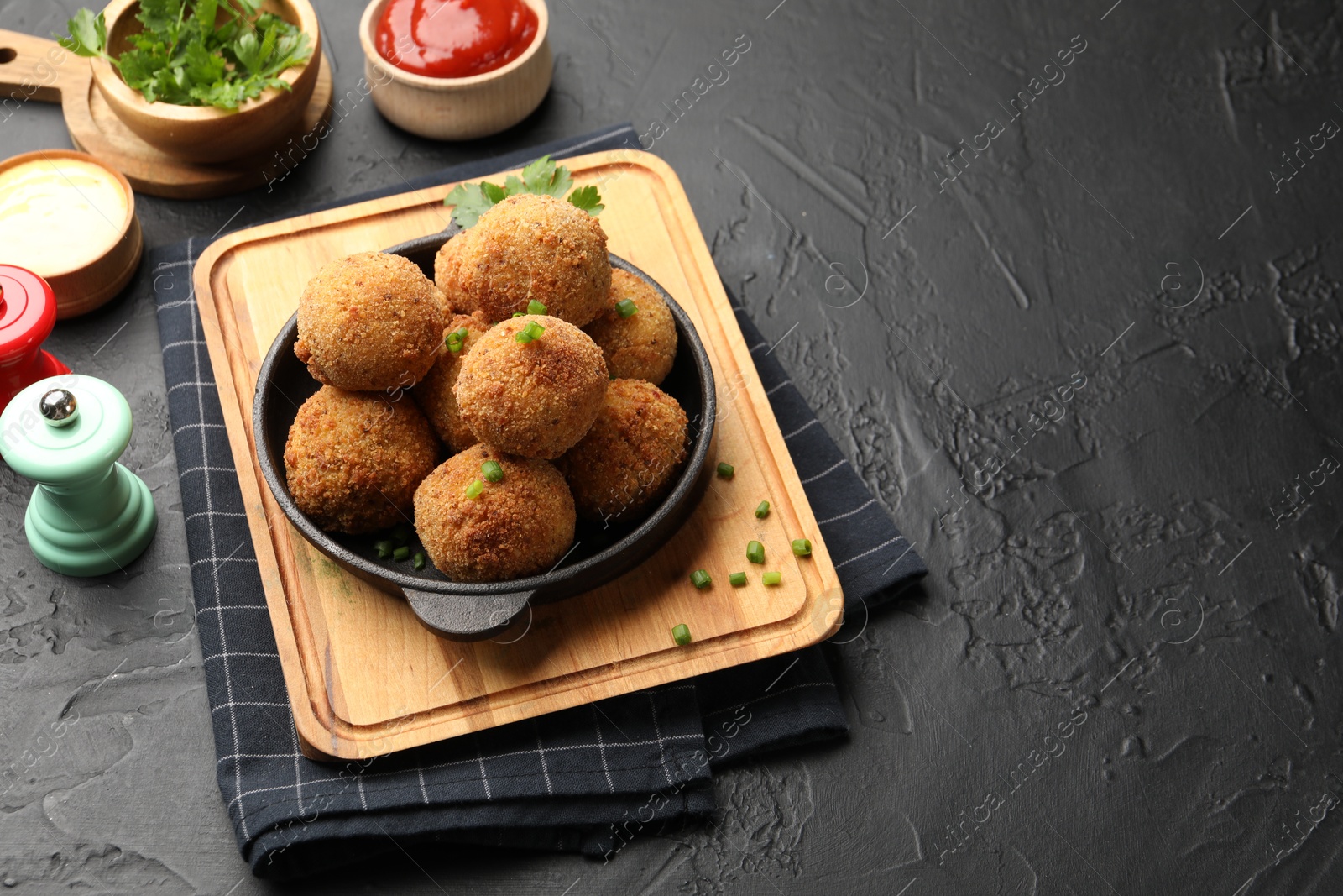 Photo of Delicious fried croquette balls with parsley and green onion on grey textured table. Space for text
