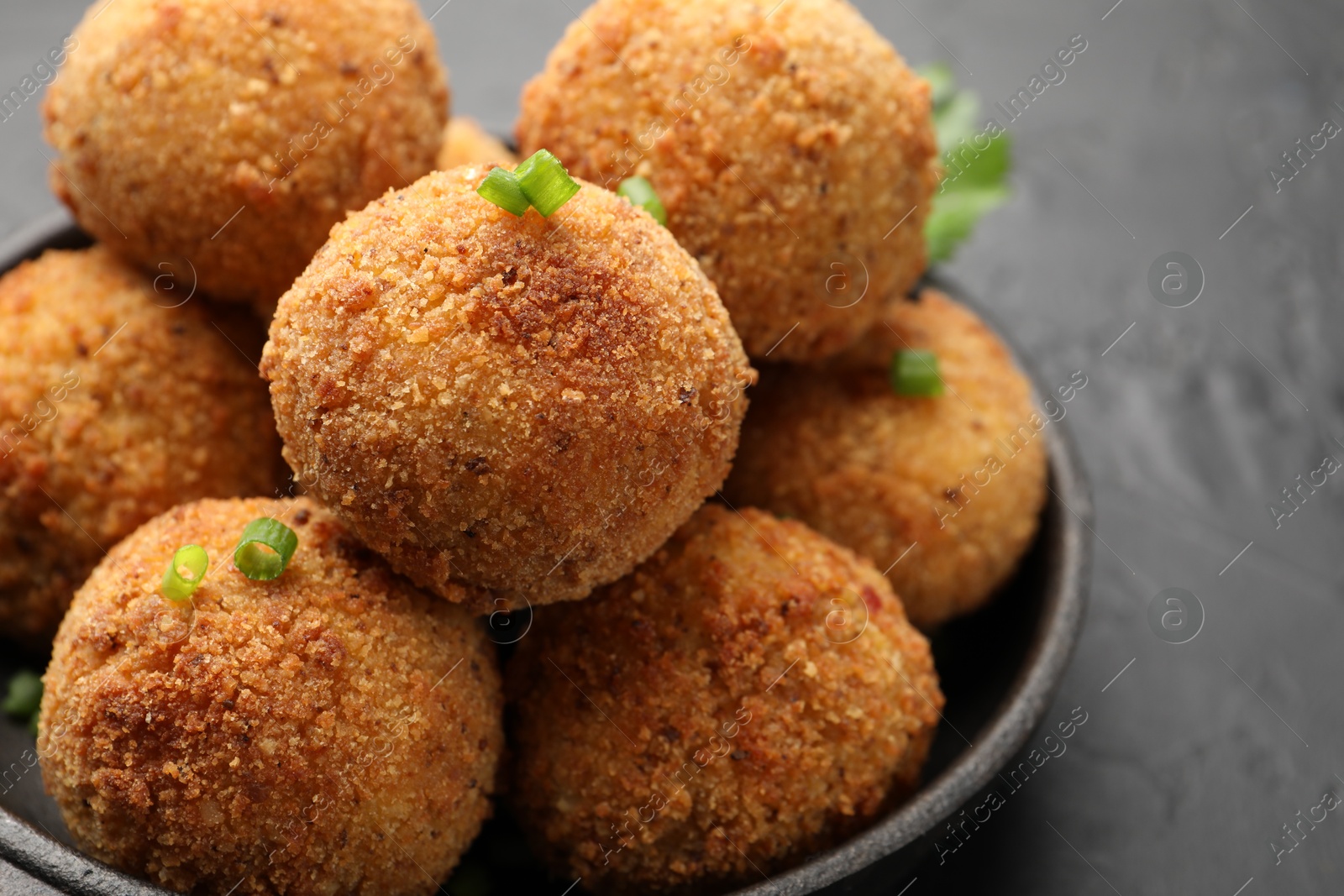 Photo of Delicious fried croquette balls with green onion on grey table, closeup