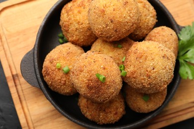 Photo of Delicious fried croquette balls with green onion on dark table, top view