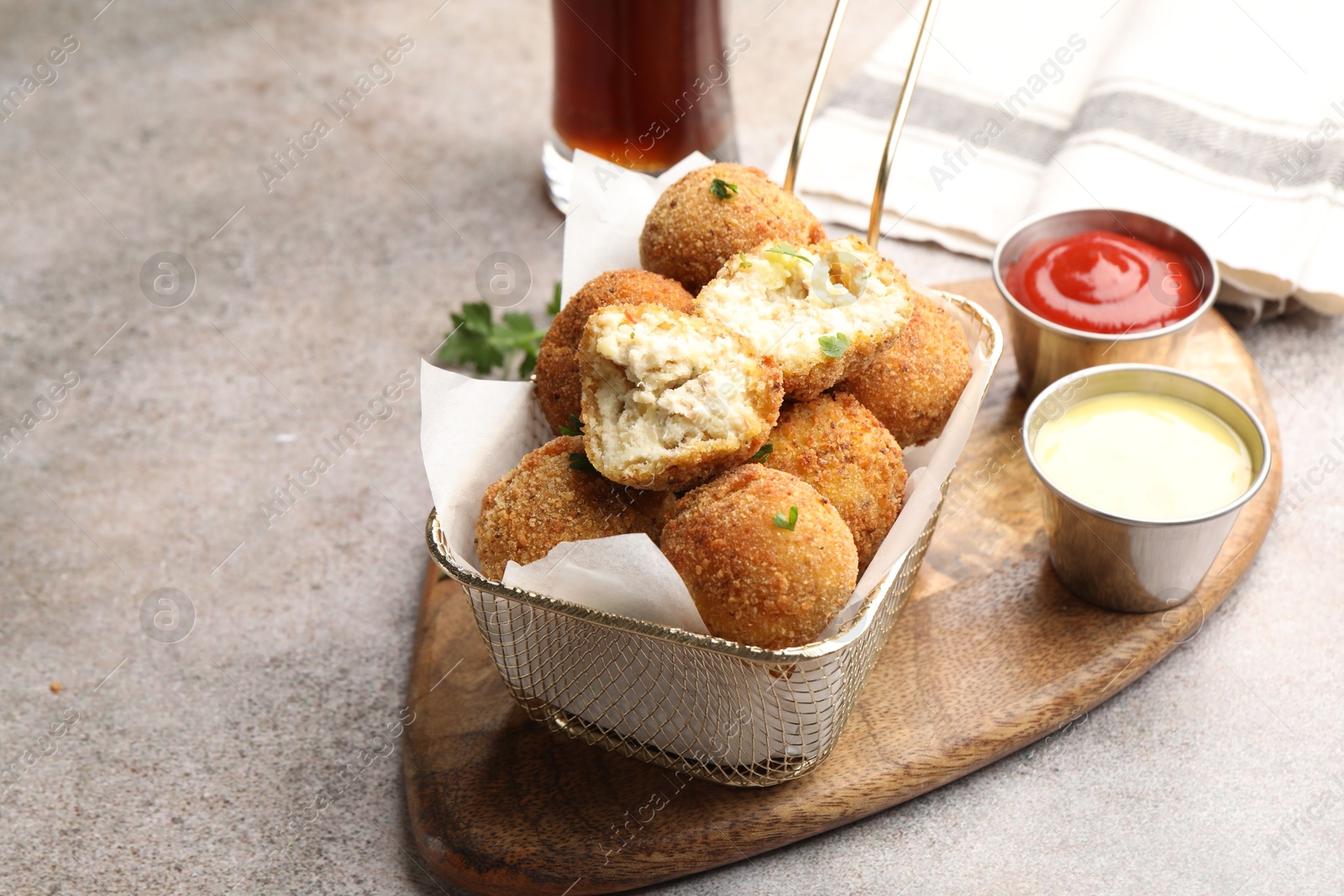 Photo of Delicious fried croquette balls with parsley and sauces on grey textured table, closeup. Space for text