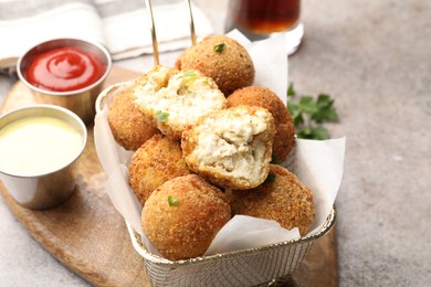 Photo of Delicious fried croquette balls and sauces on grey textured table, closeup